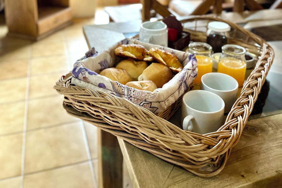 A breakfast tray with bread, juice, and a mug on a table in a room with wooden furniture and a TV.