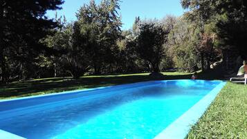 Una piscina azul cristalina rodeada de césped y árboles.