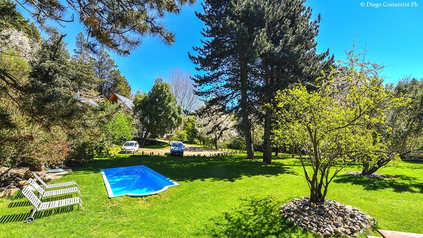 A backyard with a swimming pool, a wooden bench, and a picnic table. - Apart Hotel Rucaleufú (San Martín de los Andes)