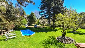 Un patio trasero con piscina, banco de madera y mesa de picnic.