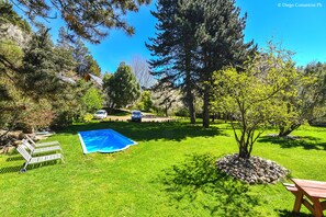 A backyard with a swimming pool, a wooden bench, and a picnic table. - Apart Hotel Rucaleufú (San Martín de los Andes)