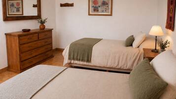 A bedroom with a bed, a dresser, a nightstand, a lamp, and two framed artworks on the wall.