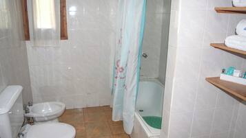 A bathroom with a toilet, bidet, bathtub, and a shower curtain.