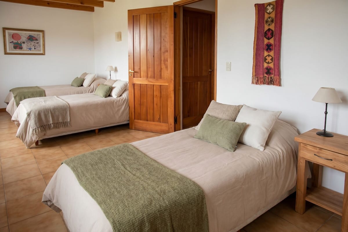 A room with two beds, a wooden door, a lamp, and a tapestry.