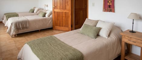 A room with two beds, a wooden door, a lamp, and a tapestry.