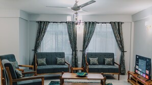 A living room with two sofas, a coffee table, and a TV stand. - St. Benedict House (Moshi)