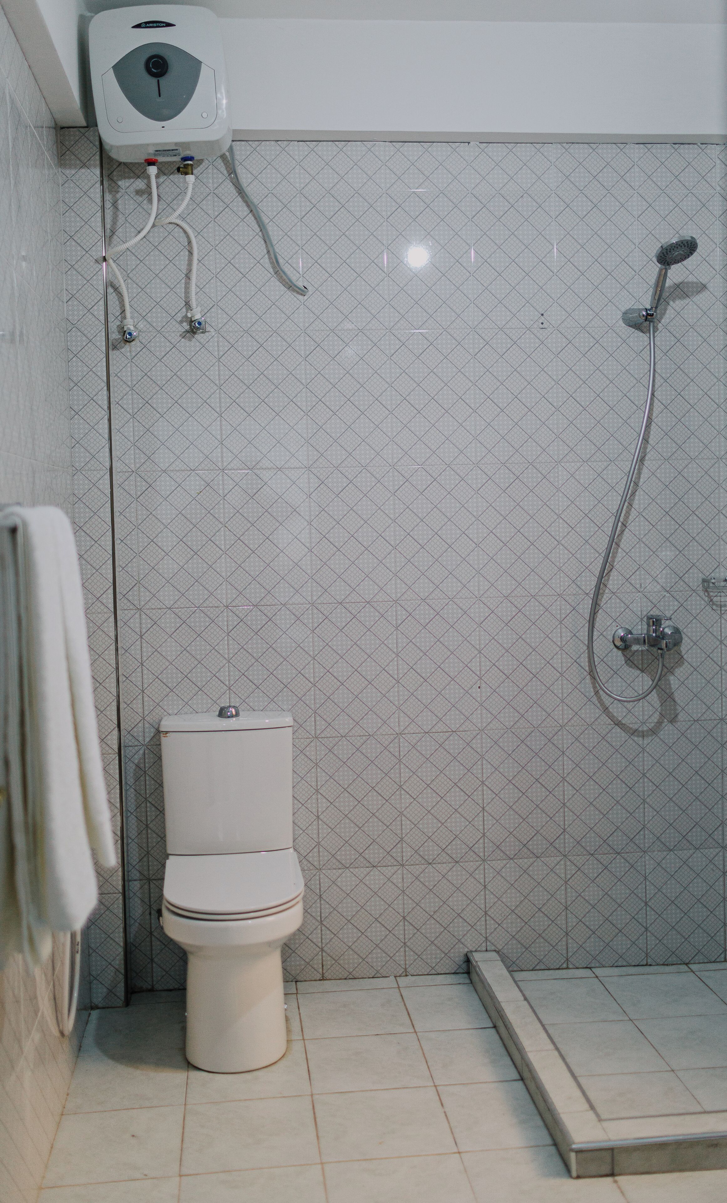 A bathroom with a toilet, a shower, and a water heater.