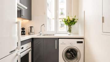 Cuina compacta amb rentadora integrada, un lavabo i una finestra a sobre.