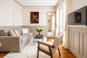 A modern living room with a sofa, armchair, and a coffee table. - 1539 Belles Feuilles (Paris)