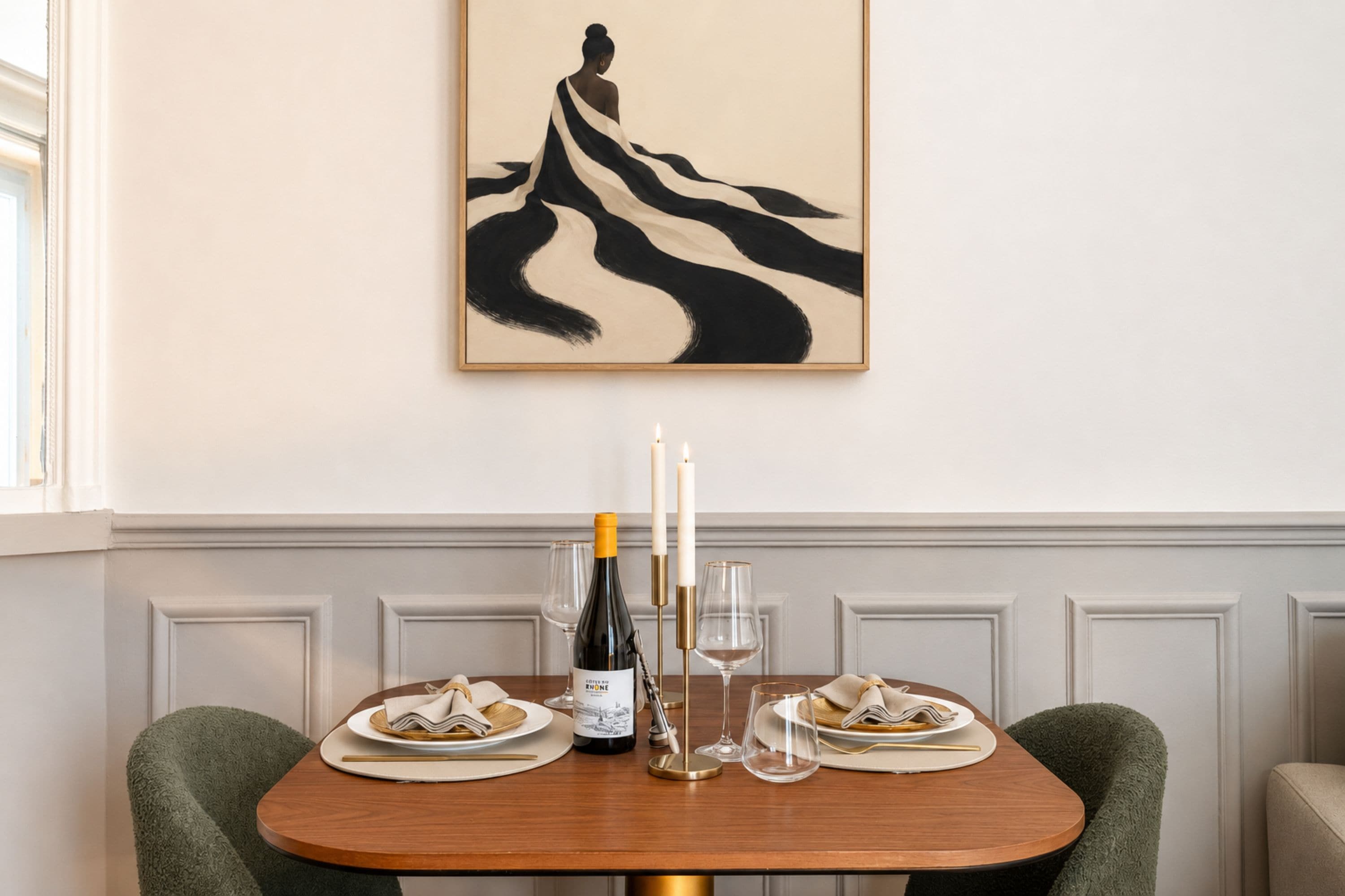 Una mesa de comedor preparada con platos, una botella de vino, copas y una vela.