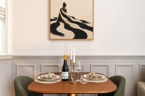 A dining table set with plates, a bottle of wine, glasses, and a candle. - 1539 Belles Feuilles (Paris)