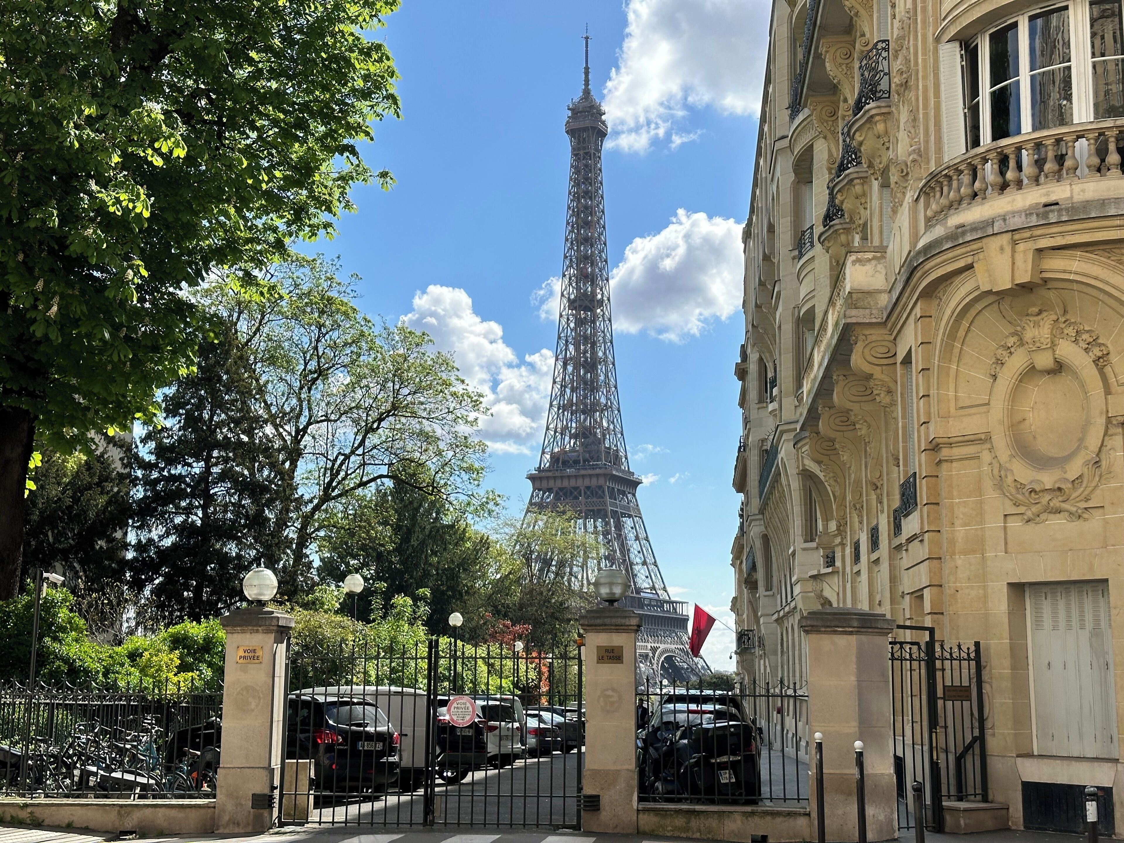 Vista de la Torre Eiffel con un edificio de arquitectura ornamentada en primer plano.