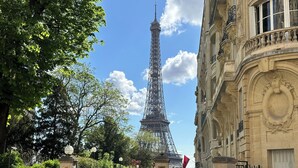 A view of the Eiffel Tower with a building featuring ornate architecture in the foreground. - 1539 Belles Feuilles (Paris)