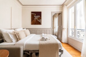 A hotel room with a bed, a painting on the wall, and a view of the outside. - 1539 Belles Feuilles (Paris)