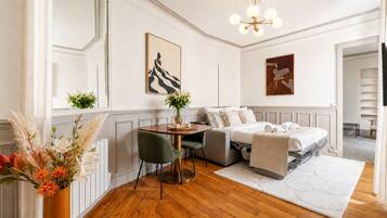 Ein Hotelzimmer mit Bett, Schreibtisch, Stuhl, Blumen in einer Vase und Kunstwerken an den Wänden.