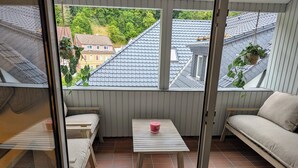 A balcony with a view of neighboring houses, a small table with a pink container, and a sofa. - A vacation with a view, a pleasant break in the heart of the city Dogs welcome (Bad Lauterberg)