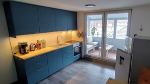 A compact kitchen with blue cabinets, a sink, and a refrigerator. - A vacation with a view, a pleasant break in the heart of the city Dogs welcome (Bad Lauterberg)