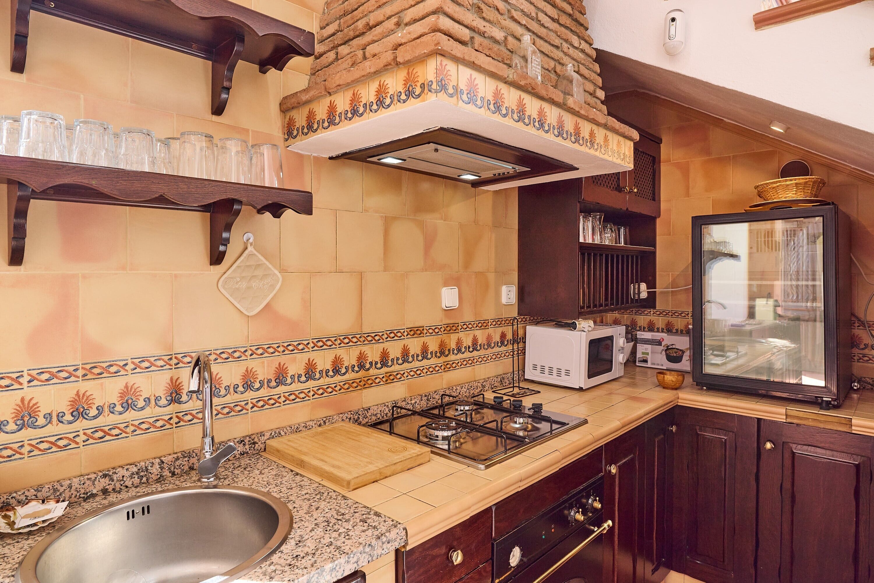 Une cuisine équipée d’un évier, d’une cuisinière, d’un four à micro-ondes et ornée de carreaux décoratifs.