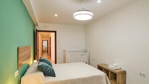 A bedroom with a bed, bedside table, and a crib.