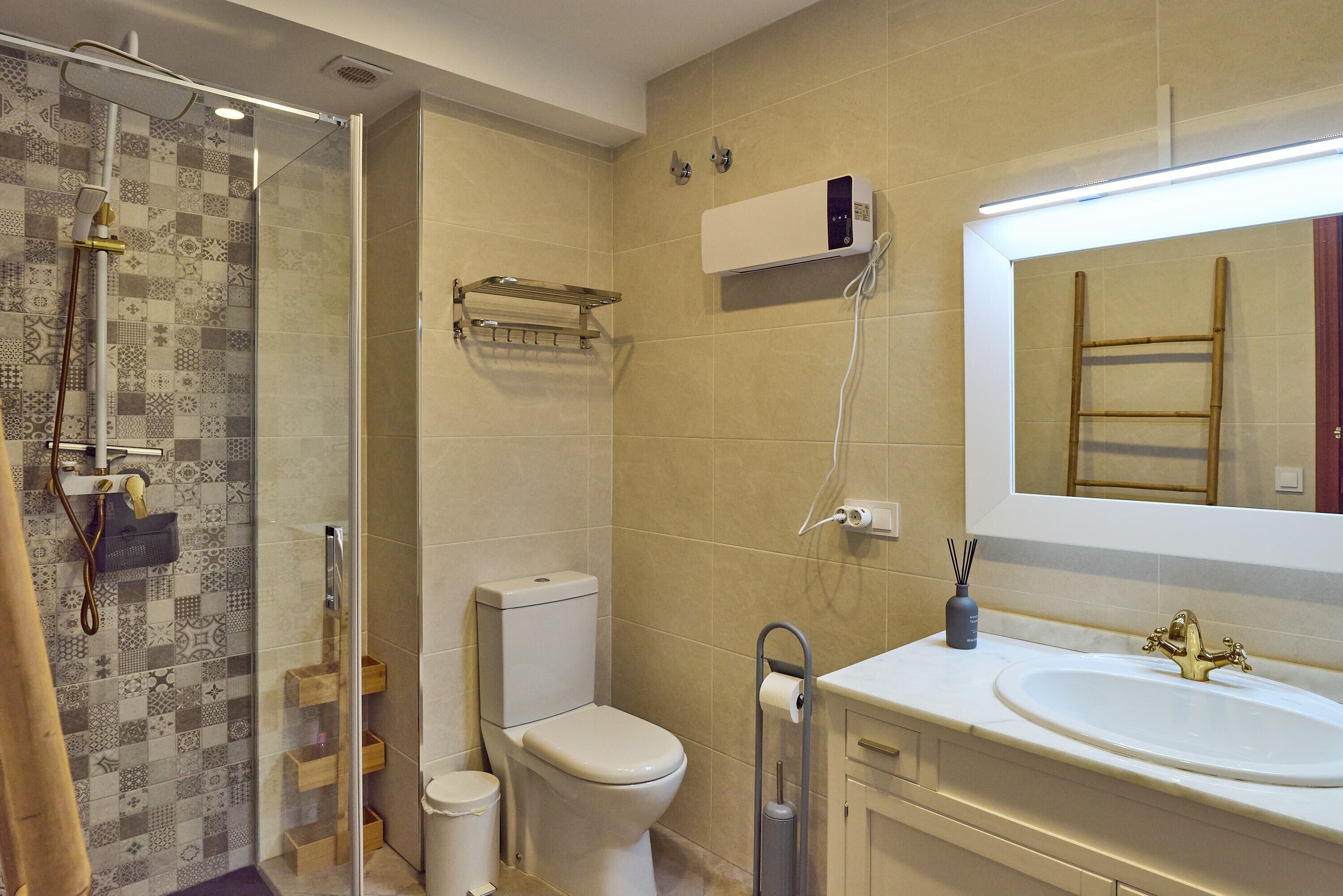 A bathroom with a shower, toilet, sink, and a mirror.