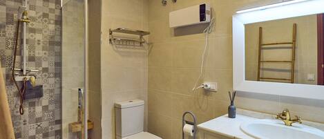 A bathroom with a shower, toilet, sink, and a mirror.