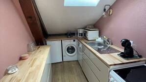 Cocina compacta con tragaluz, lavadora, cafetera y estufa.