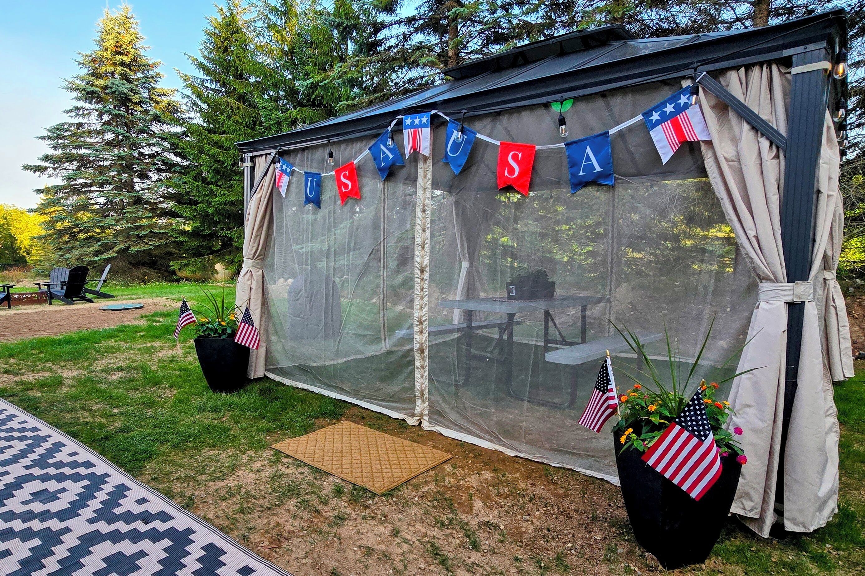Ett avskärmat utomhusområde med bord och stolar, dekorerat med amerikanska flaggor och en banderoll med texten ”USA”.