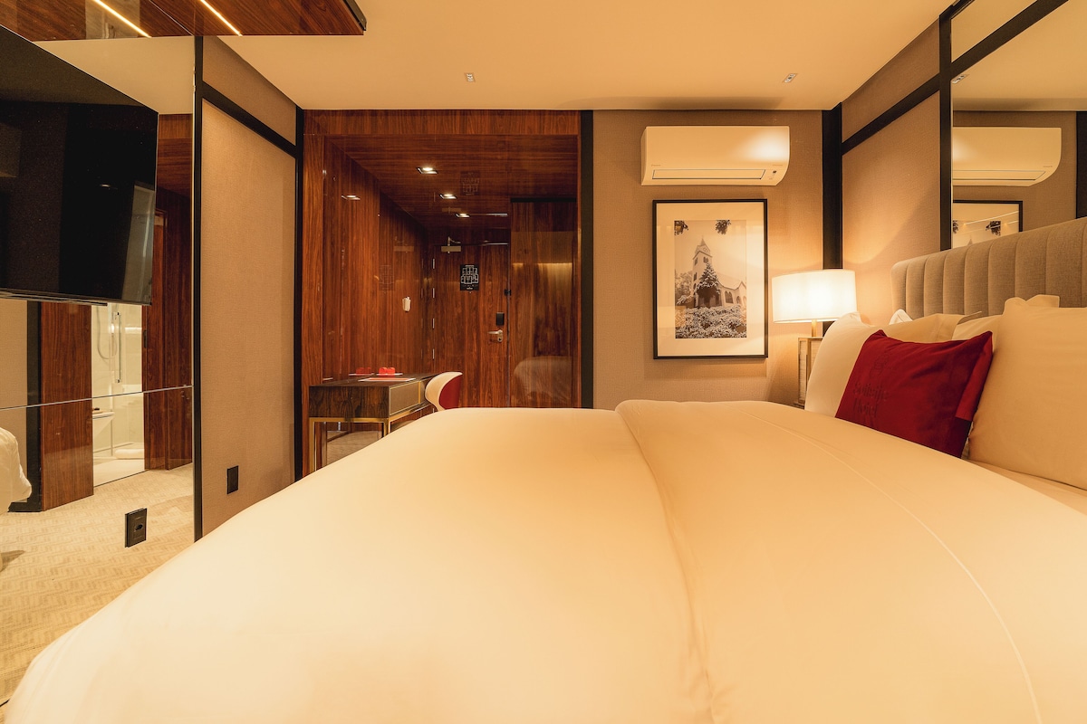 A hotel room with a large bed, a desk with a chair, a television, and a framed picture on the wall.