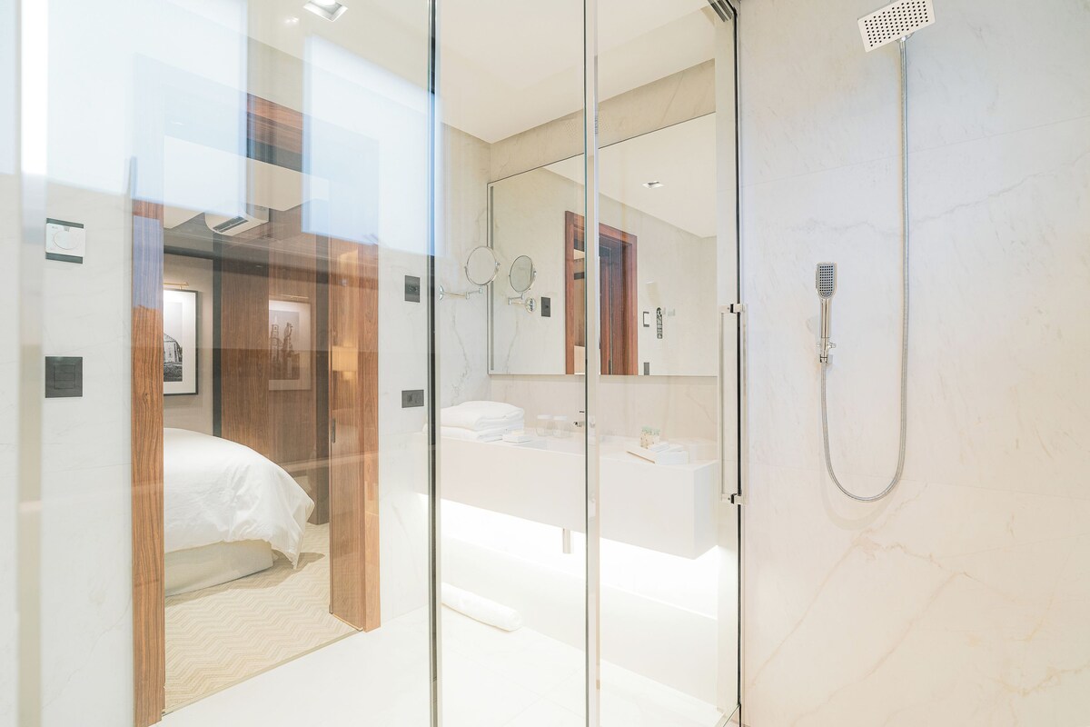 A modern bathroom with a glass partition, a shower, a sink, and a mirror.