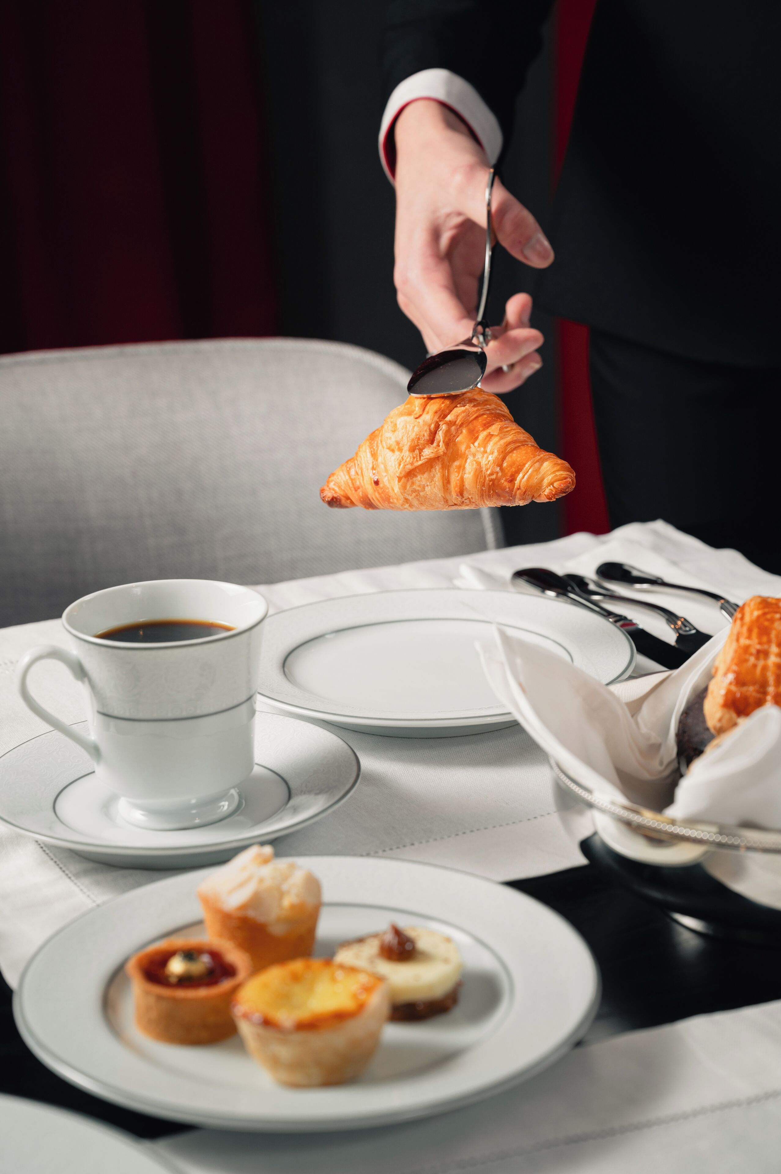 A table with a cup of coffee, plates, and pastries.