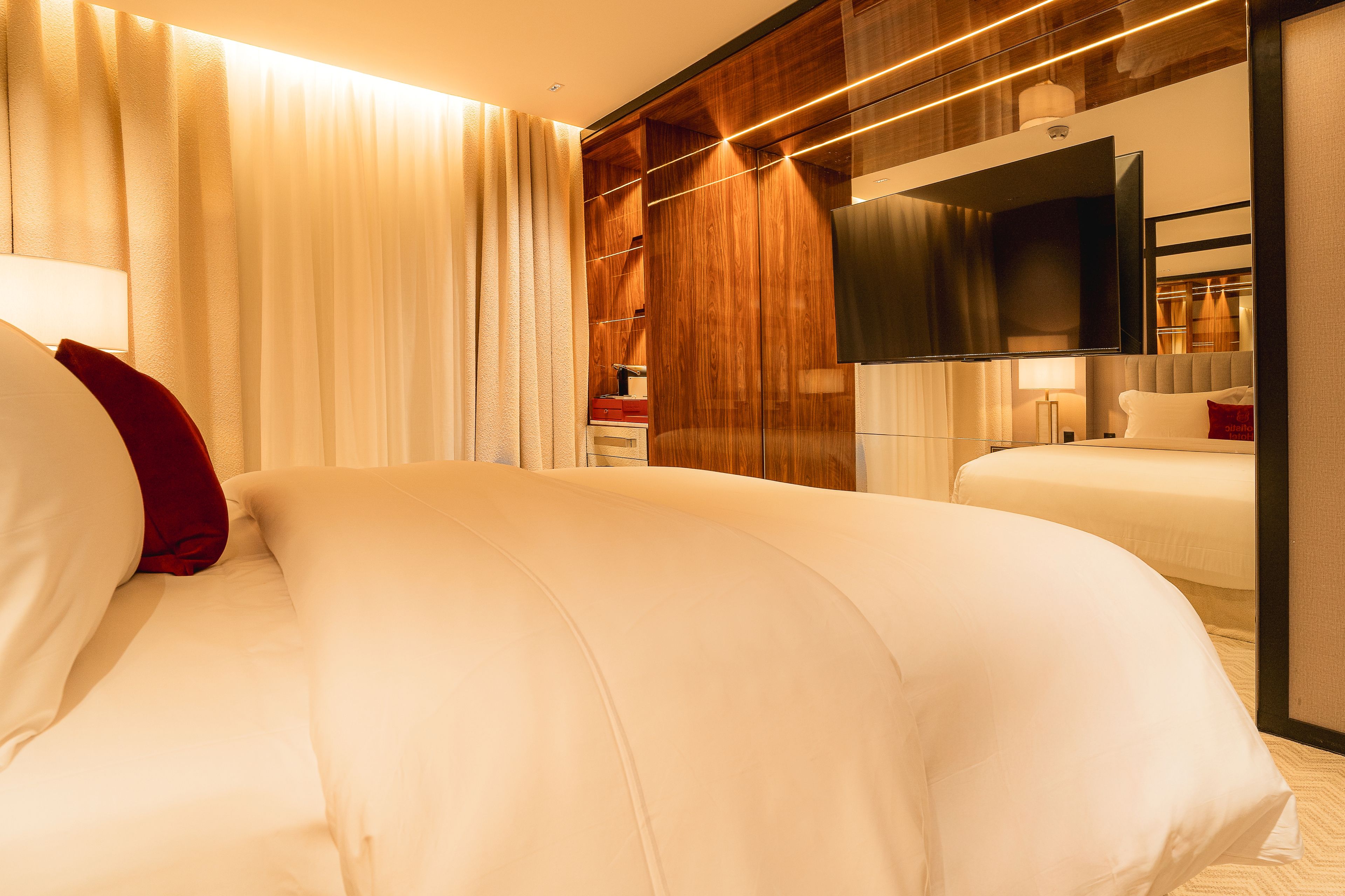 A hotel room with a large bed, a TV, and a wooden wardrobe.
