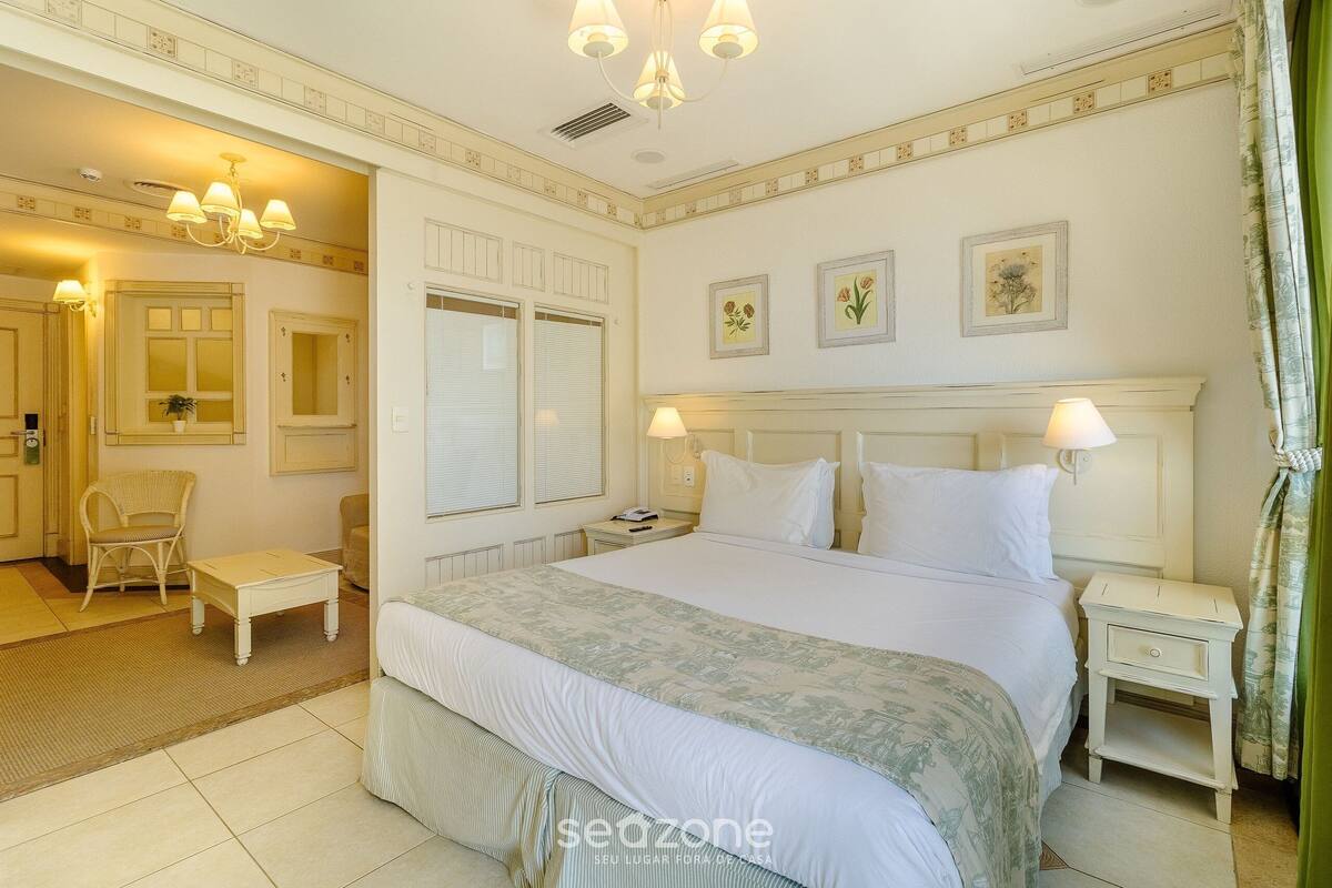 Habitación de hotel con una cama grande, dos mesitas de noche, una silla y una pequeña mesa.