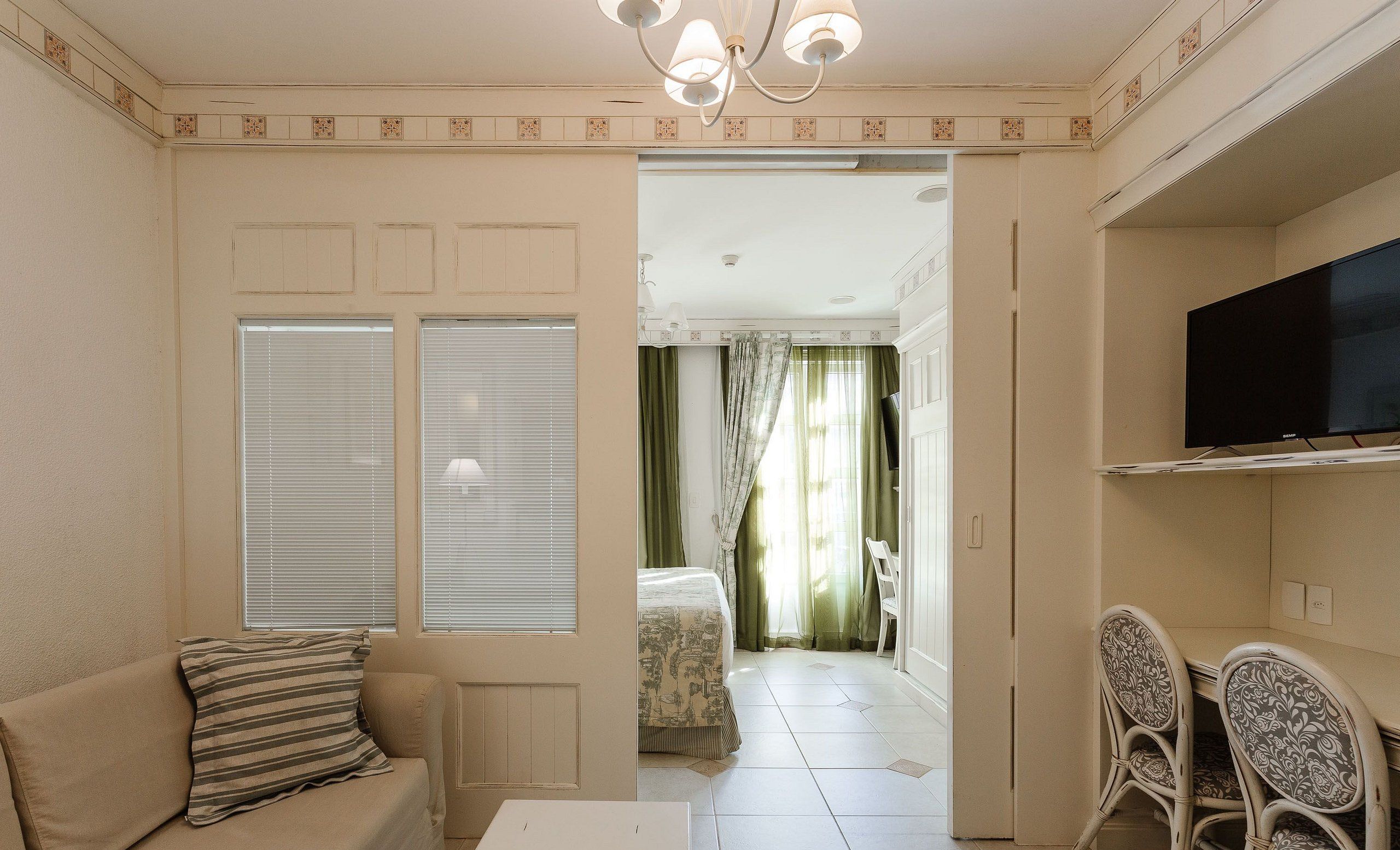 A living room with a sofa, a TV, and a dining area with chairs.