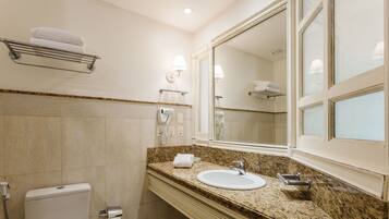 A bathroom with a sink, mirror, towel rack, and a towel dispenser.