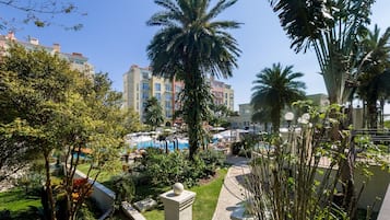 Un resort con piscina, palmeras y vistas de edificios cercanos.