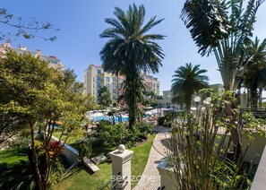 A resort with a swimming pool, palm trees, and a view of nearby buildings. - Charmosos Studios no IL Campanario Villaggio Resort ILCJR II (Florianópolis)