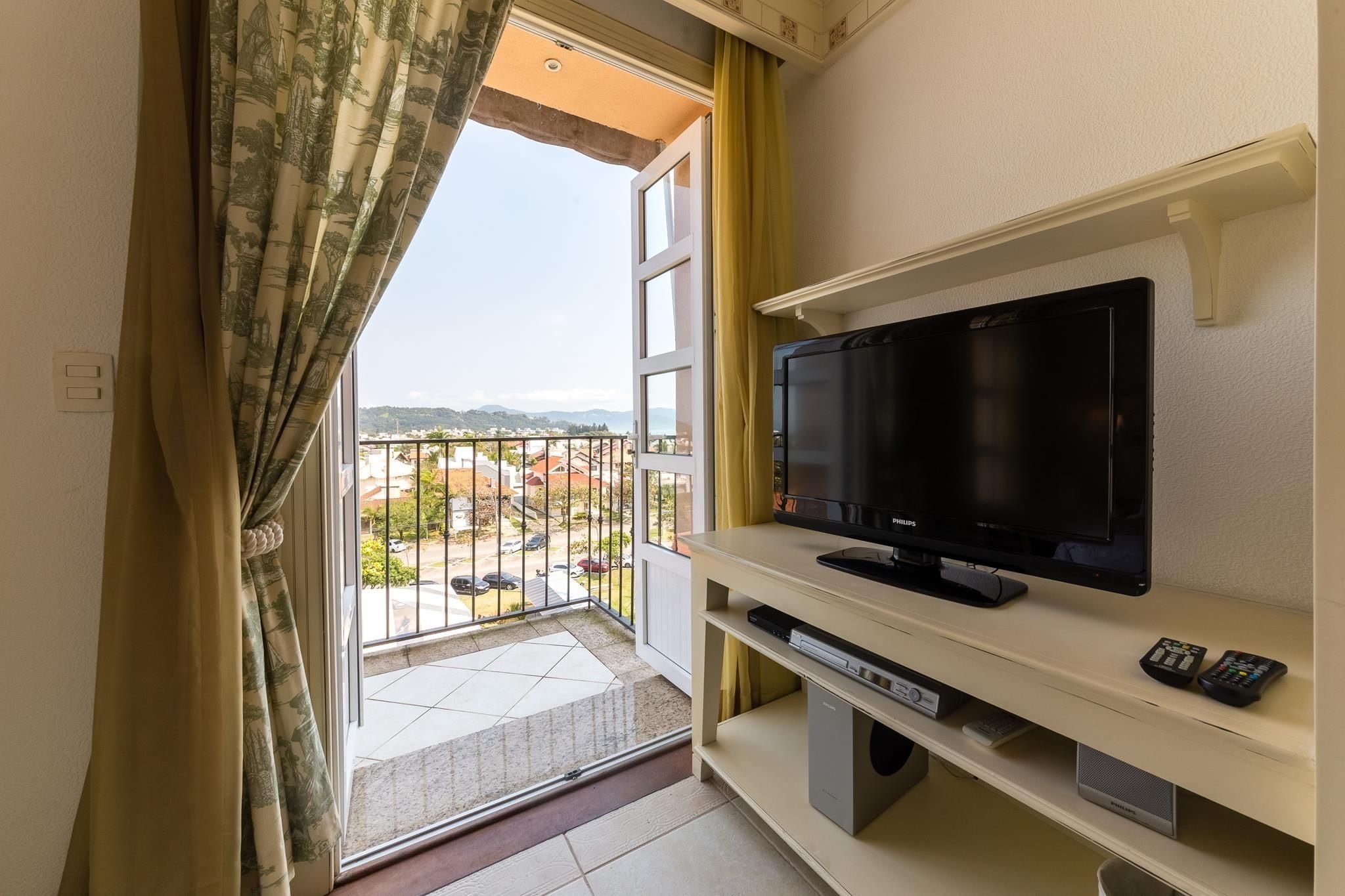 Ein Balkon mit Fernseher, Fernbedienungen und einem DVD-Player auf einem Regal.