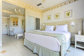 A hotel room with a large bed, a bedside table, a chair, and a window with blinds. - Charmosos Studios no IL Campanario Villaggio Resort ILCJR II (Florianópolis)