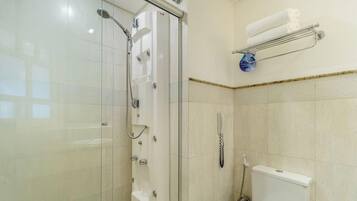Un baño con ducha de vidrio, inodoro y toallero con una toalla doblada.