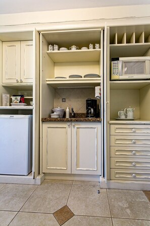 A compact kitchen with white cabinets, a microwave, a coffee maker, and a refrigerator. - Charmosos Studios no IL Campanario Villaggio Resort ILCJR II (Florianópolis)