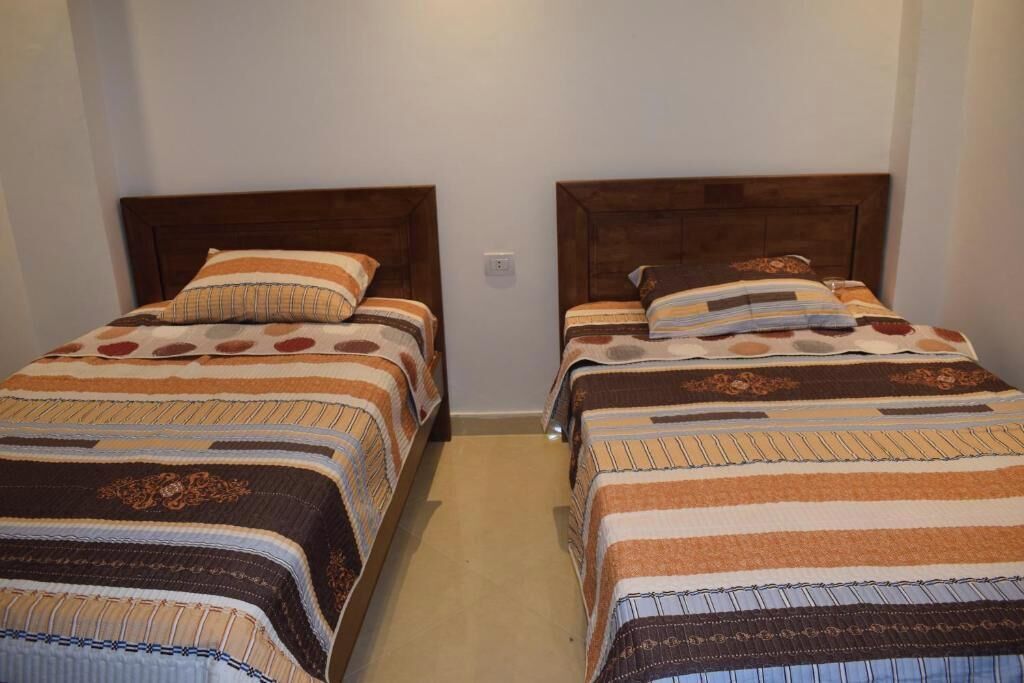 Ein Zimmer mit zwei Betten, jeweils mit Holz Kopfteil und gestreifter Bettwäsche.