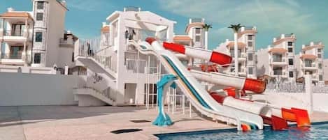 A pool area with a water slide and a pool.