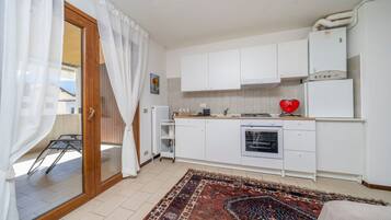 Una cucina compatta con mobili bianchi, un fornello e un frigorifero.