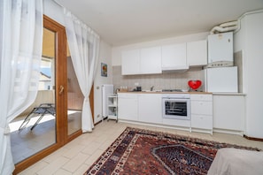 A compact kitchen with white cabinets, a stove, and a refrigerator.