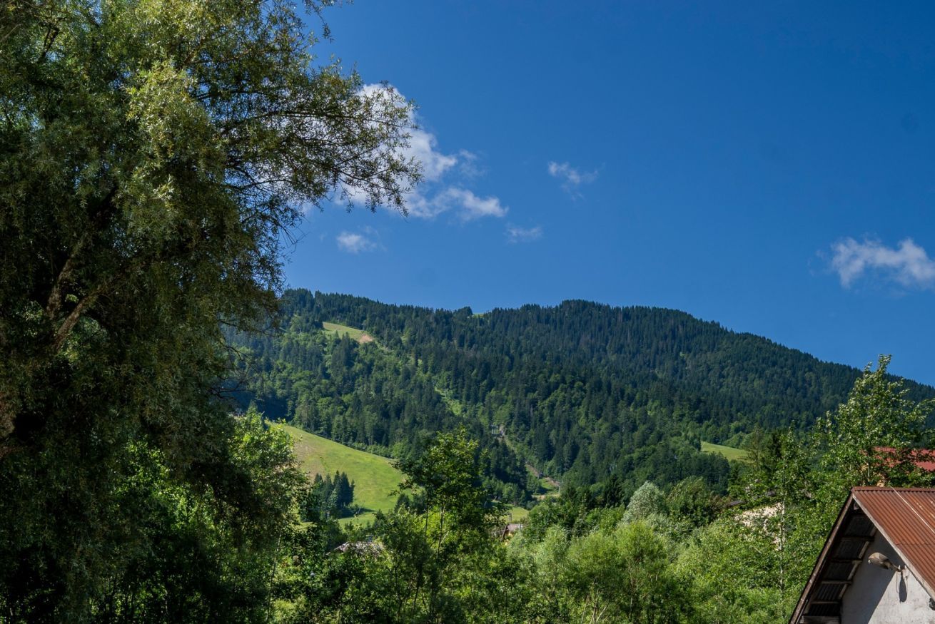 A mountain landscape with a house in the foreground.