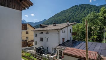 Quartiere residenziale con edifici, un'auto e montagne sullo sfondo.