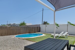Un jardin avec une piscine, un patio couvert et un espace détente avec des chaises longues.
