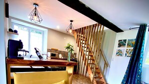 Ein modernes Wohnzimmer mit einem gelben Sofa, einer Holztreppe und einem Küchenbereich.