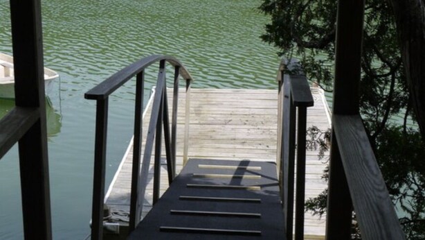 Un muelle de madera con barandilla de metal que conduce a un bote.