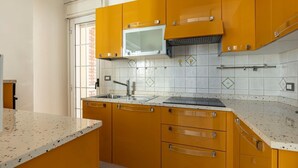 Una cocina con armarios amarillos, un lavamanos de acero inoxidable y un salpicadero de azulejos.